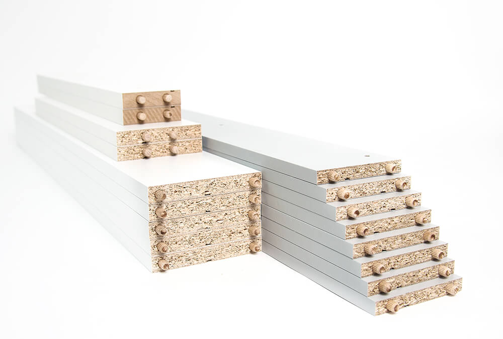 Pile de panneaux de particules blancs avec des chevilles en bois.