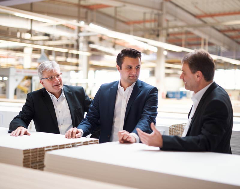 Three men discussing in a factory hall.